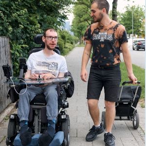 freiwilliger begleitet rollstuhlfahrer in der freizeit