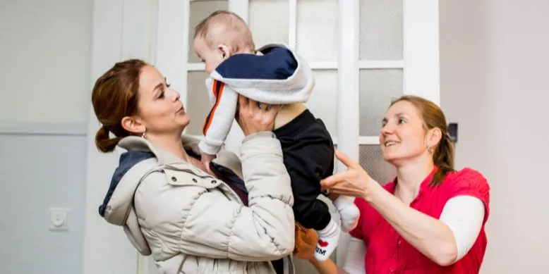 Freiwillige von wellcome hebt Baby hoch