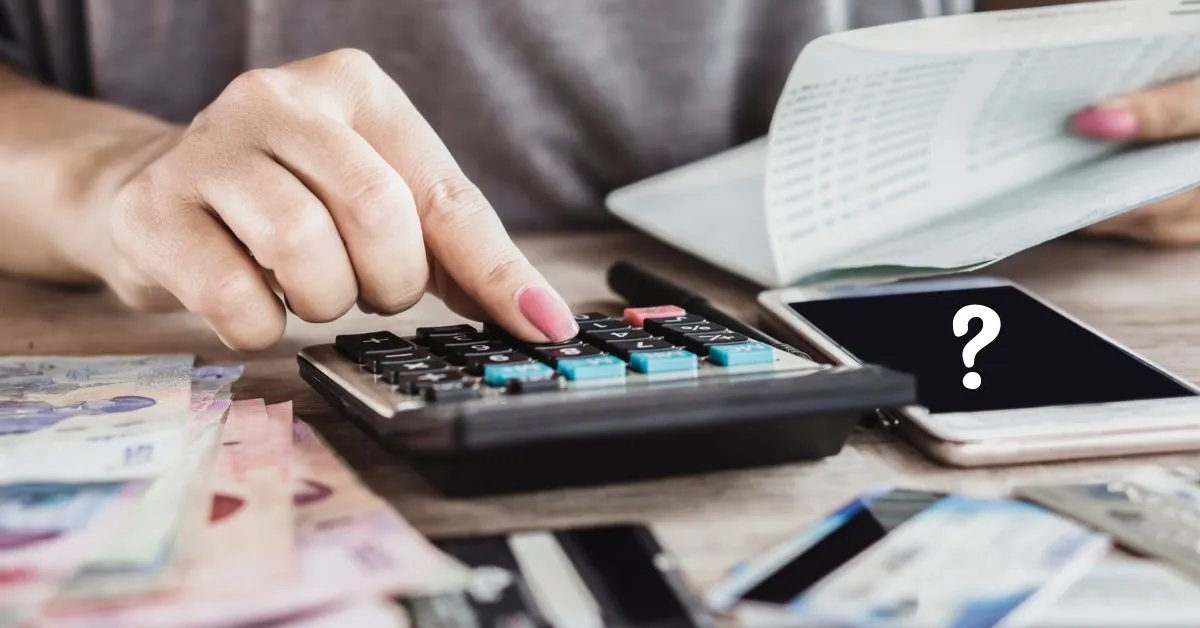 Hände am Taschenrechner daneben Geld und Rechnungen